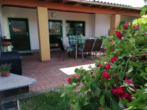 eine Terrasse mit einem Tisch, Stühlen und Rosen in der Unterkunft Ferienhaus Putzke in Stadtilm