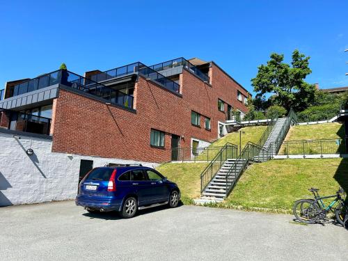 um carro azul estacionado em frente a um edifício de tijolos em Simple room em Trondheim