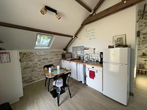 une cuisine avec une table et un réfrigérateur dans l'établissement Ty Sau Hiol, La Moniclair, à Péaule