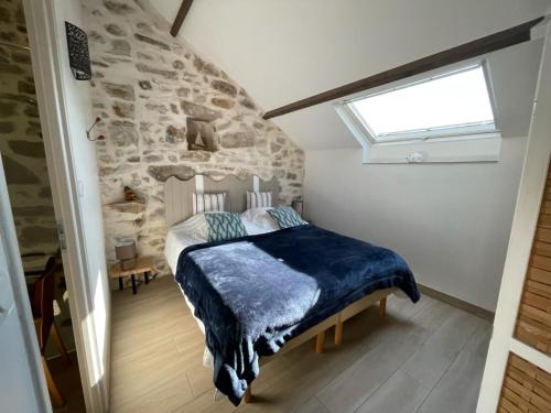 una camera con un letto in una stanza con un muro in pietra di Ty Sau Hiol, La Moniclair a Péaule