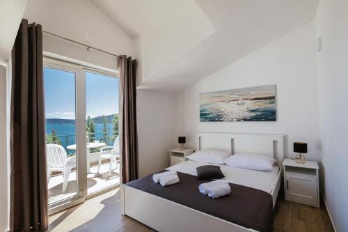 a bedroom with a bed and a balcony at Apartments M in Seget Vranjica