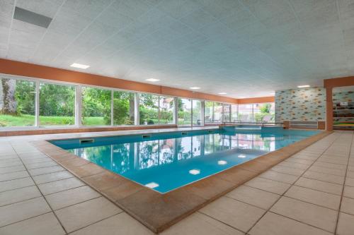 a large swimming pool in a building with windows at Hôtel d'Angleterre (by Popinns) in Vittel