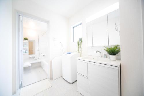 a white bathroom with a sink and a toilet at Nagashima Riverside Resort 2 in Hakuro