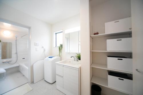 y baño blanco con lavabo y ducha. en Nagashima Riverside Condominium, en Hakuro