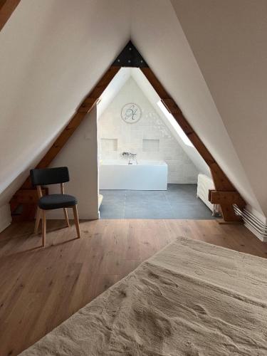 Cette chambre mansardée comprend une chaise et un lit. dans l'établissement STUDIO Villa vacances, à Le Touquet-Paris-Plage