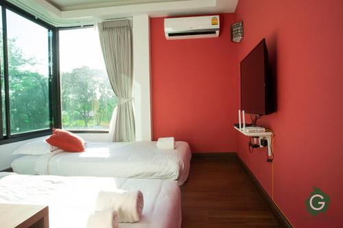 twee bedden in een kamer met rode muren en een tv bij Green@Buriram in Buriram