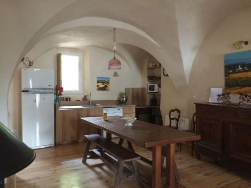 une cuisine avec une table et un réfrigérateur blanc dans l'établissement Maison de village en montagne, à La Bréole