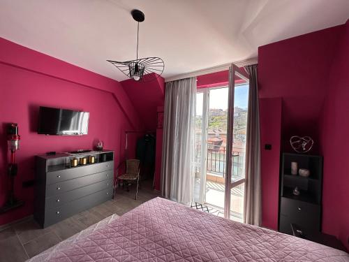 Habitación de color rosa con cama y ventana en Sea Sky View Apartments en Balchik