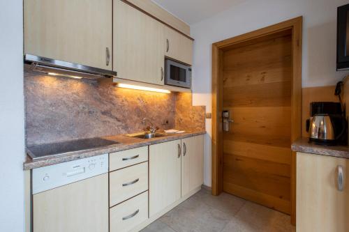 a kitchen with white cabinets and a sink and a door at Gidis Hof in Ischgl