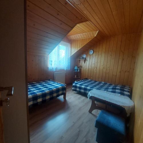 a room with two beds in a wooden cabin at Pokoje Gościnne u Huberta in Soblówka