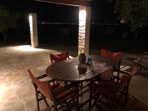 a wooden table and chairs on a patio at night at House by the Sea at Skaloma, Loutraki in Vouliagmeni Lake
