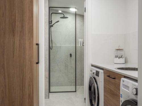 a bathroom with a shower and a washing machine at Central Bendigo Cottage Charm in Bendigo