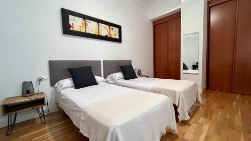 1 dormitorio con 2 camas con sábanas blancas en Picassia Home Malaga Center, en Málaga