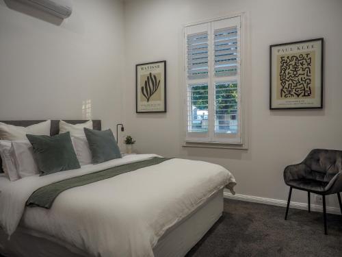 a bedroom with a bed and a window and a chair at Central Bendigo Cottage Charm in Bendigo