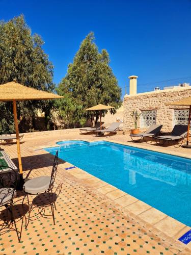 a swimming pool with chairs and umbrellas next to a building at Villa Nouran Beldi 2Chambres in Essaouira