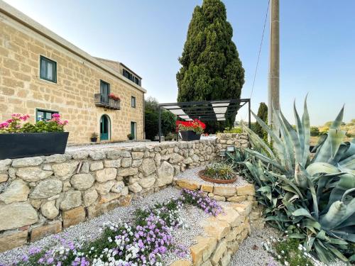 a stone wall with flowers in front of a building at La Casa del Poeta Enna - Pergusa in Enna