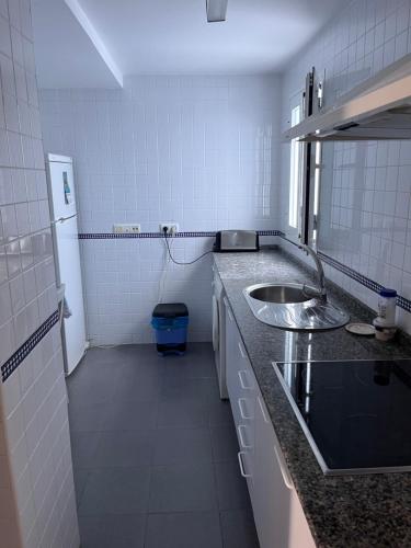 uma pequena cozinha branca com um lavatório e um espelho em Vejer luz em Vejer de la Frontera