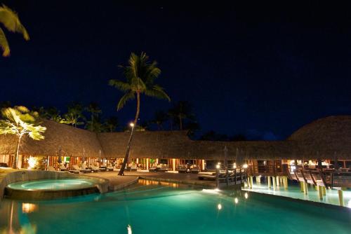 a resort with a swimming pool at night at Hotel Kia Ora Resort & Spa in Avatoru