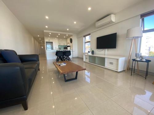 a living room with a couch and a tv and a table at Redvue Holiday Apartments in Redcliffe