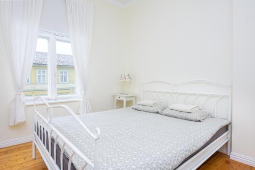 1 cama blanca en un dormitorio blanco con ventana en Ringi Apartments, en Pärnu