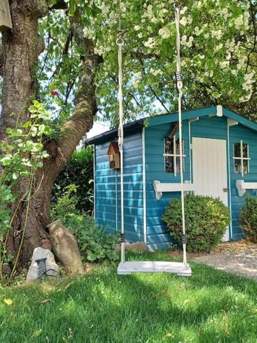 a blue house with a swing in front of a tree at Ferienwohnung An den Linden in Kelmis