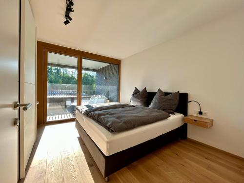 1 dormitorio con 1 cama grande y puerta corredera de cristal en Seeparkvilla – Wohlfühlen am See und im Grünen en Bregenz