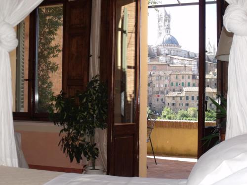 a bedroom with a bed and a view of a city at Residenza d'Epoca Campo Regio Relais in Siena