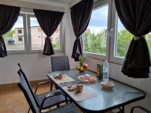 a table with two chairs and a table with fruit on it at Apartmani 'Cvit' in Karlobag