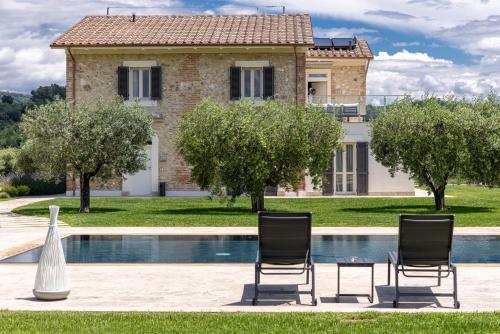 a villa with a swimming pool and two chairs at TENUTA FOGLIANI Resort & Natural Spa in Visciano