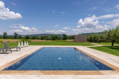 a swimming pool with two lawn chairs and a field at TENUTA FOGLIANI Resort & Natural Spa in Visciano