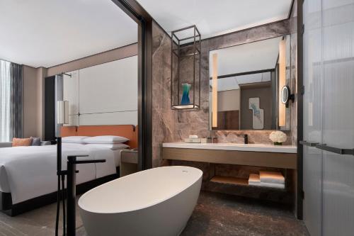 a bathroom with a tub and a bed and a mirror at Tianjin Marriott Hotel National Convention and Exhibition Center in Tianjin