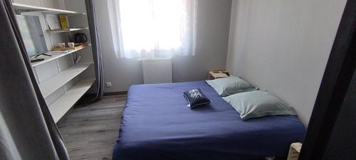 una piccola camera con letto blu e finestra di Chambre chez Sylvain a Pleurtuit