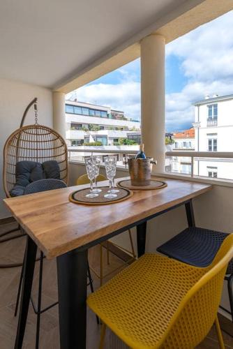 une table en bois avec deux verres et des chaises sur un balcon dans l'établissement Renovated bijou gem in heart of Cannes, à Cannes