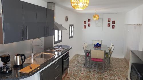 a kitchen with a sink and a table with chairs at Alan's house Asilah in Asilah