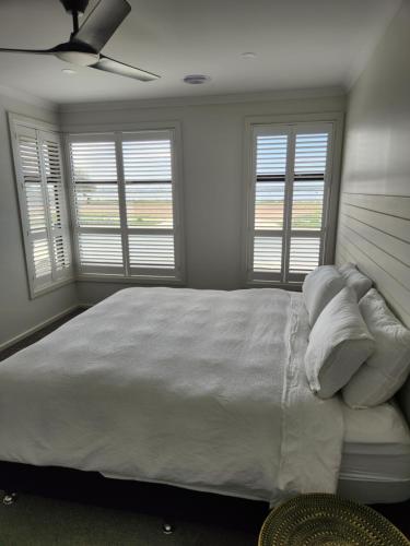 a bedroom with a large white bed with windows at Bullseye in Yarrawonga