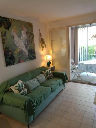 un salon avec un canapé vert et une terrasse dans l'établissement Studio Rez de jardin St Aygulf, à Fréjus