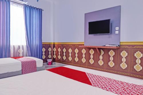 Habitación de hotel con 2 camas y TV en OYO 92518 De Luna Hotel, en Banjarbaru