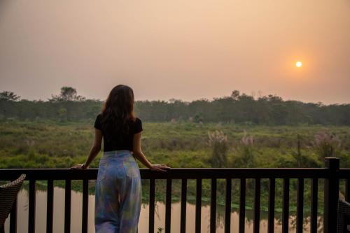 a woman standing on a balcony looking at the sunset at Jagatpur Lodge by Annapurna in Khargauli