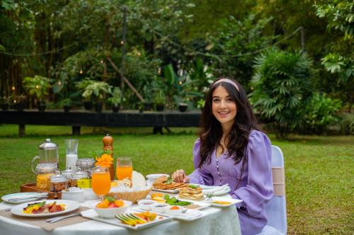 a woman sitting at a table with food at Jagatpur Lodge by Annapurna in Khargauli