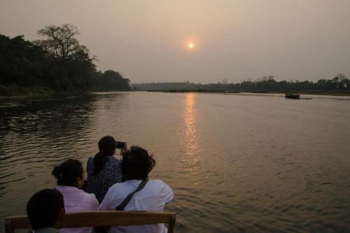 a group of people sitting on a bench looking at the water at Jagatpur Lodge by Annapurna in Khargauli