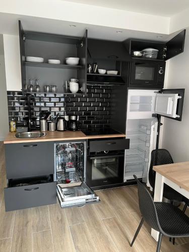 une cuisine avec des appareils noirs et une table en bois dans l'établissement Vernier, à Nice