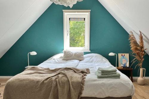 een slaapkamer met een bed met een blauwe muur en een raam bij Luxe boshuis Veluwe - Foss Lodge - luxury forest retreat in Nunspeet
