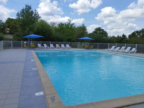 - une piscine avec des chaises et des parasols bleus dans l'établissement Pescalis Résidence Les Maisons du Lac, à Moncoutant