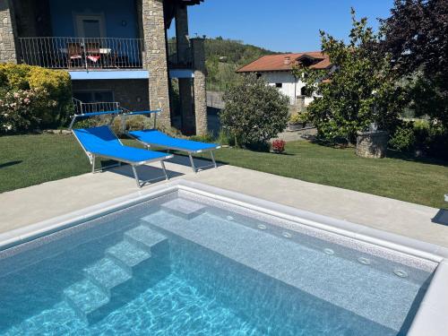 a swimming pool with two blue chairs next to a house at La Casa Blu in Montegrosso dʼAsti
