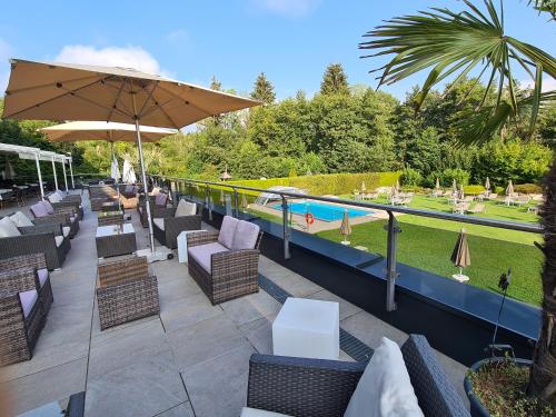 eine Terrasse mit Stühlen und Sonnenschirmen sowie einem Pool in der Unterkunft Dei Hotel Schönblick in Velden am Wörthersee