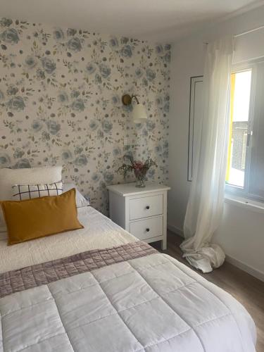 - une chambre avec un lit et une fenêtre ornée de papier peint floral dans l'établissement Casita típica de pescadores -Casa Gloria-, à Burela