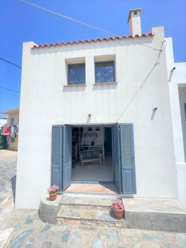 a white building with blue doors and two potted plants at The Stone House in Votsi