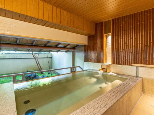 uma banheira de hidromassagem num quarto com paredes de madeira em Shuzenji Onsen Katsuragawa em Izu