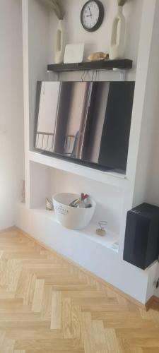 ein weißes Zimmer mit einer Uhr und einer Schale auf einem Regal in der Unterkunft Elena - Studio Apartman in Ičići