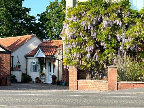 a house with a tree with purple flowers at Acorn Cottage in Ollerton